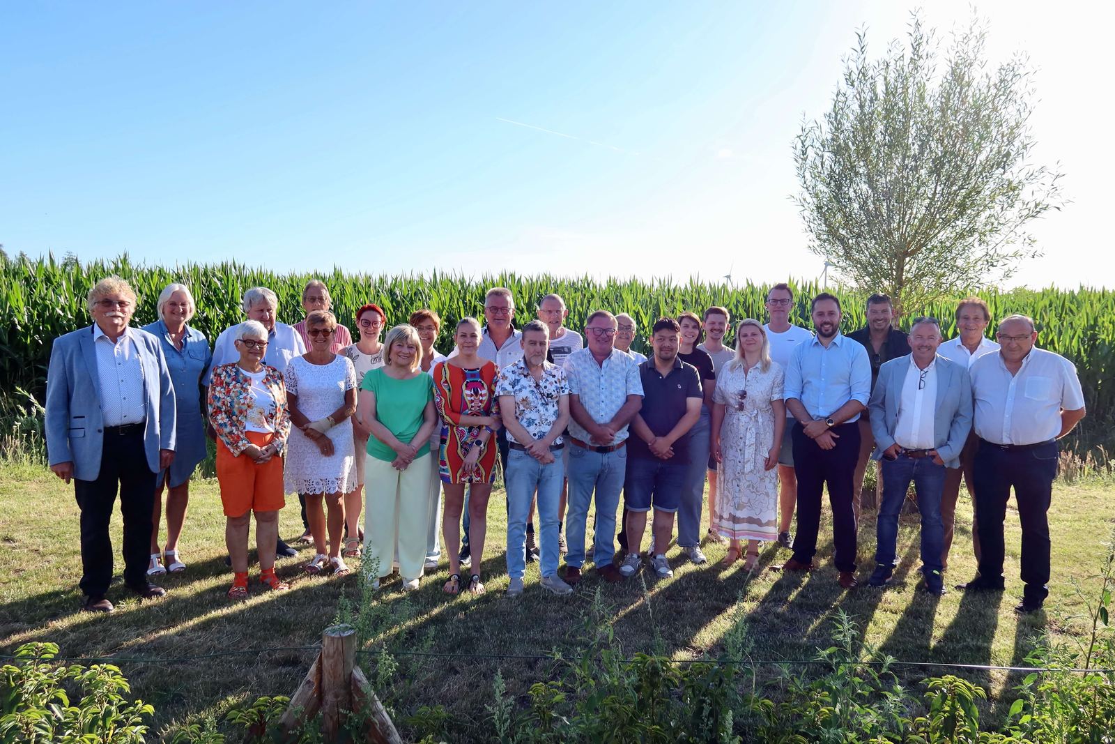 Groepsfoto van de ploeg van Team Burgemeester, samen in een maïsveld bij avondzon